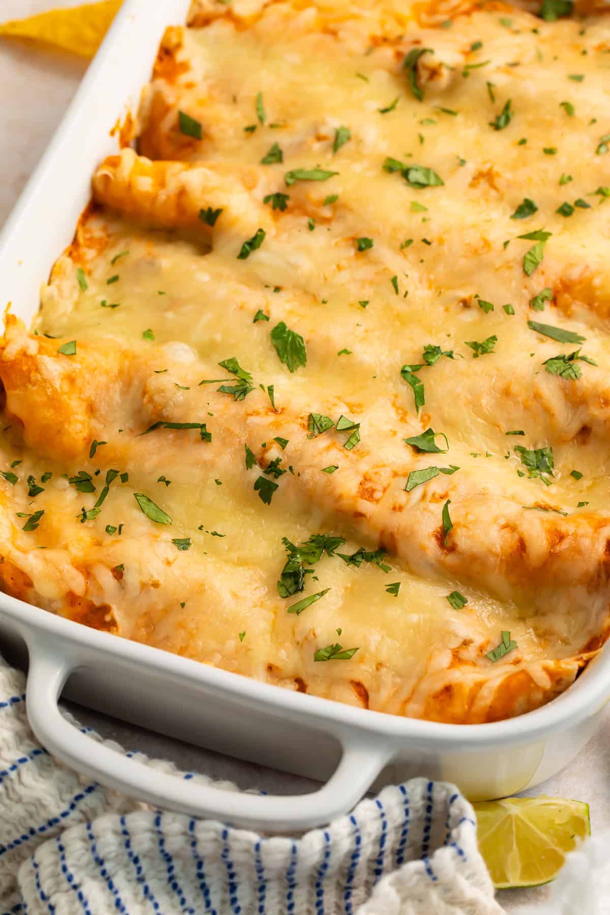 Close up of a baked pan of chicken enchiladas with lots of melted cheese.