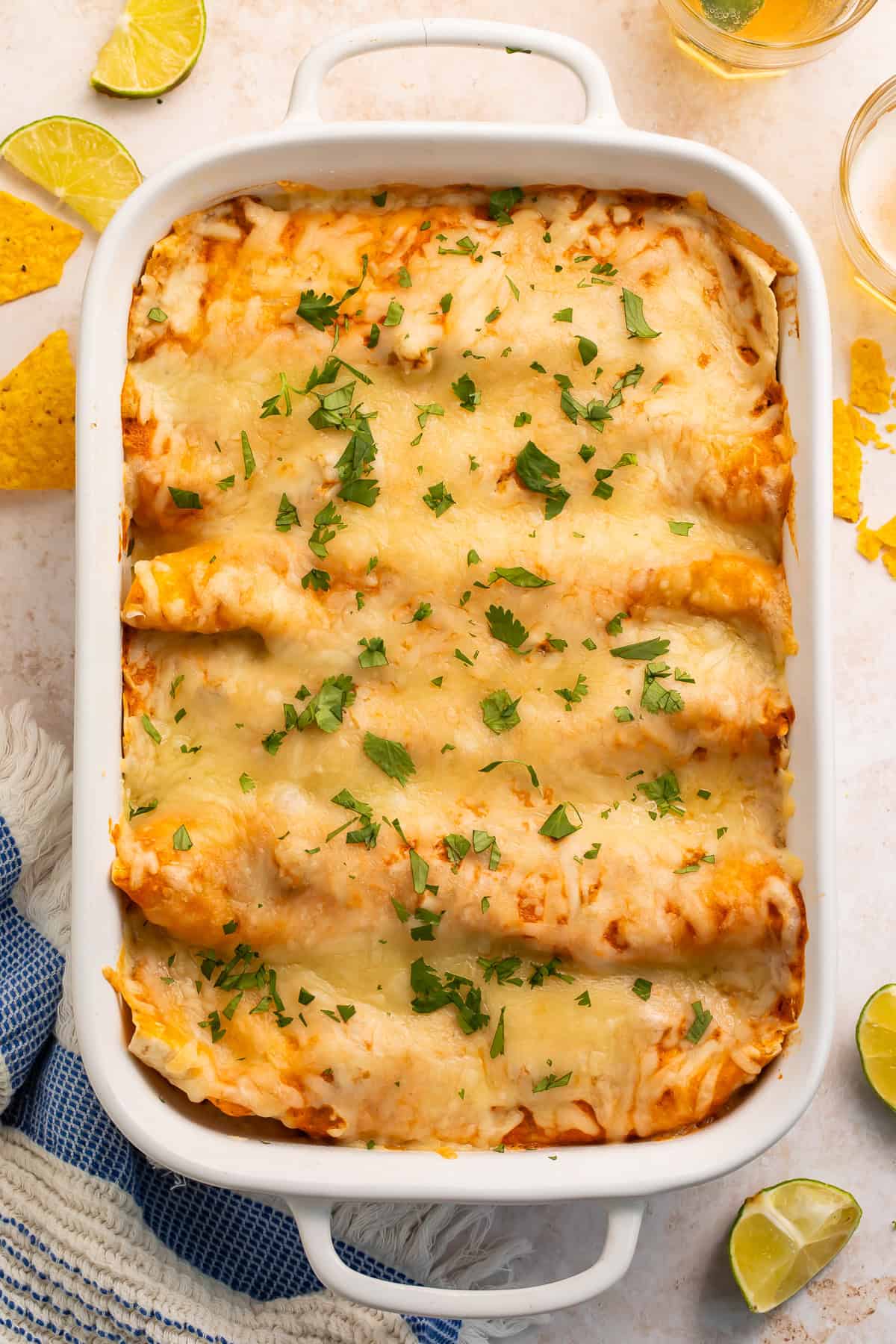 Overhead shot of baked creamy chicken enchiladas in a white baking dish.