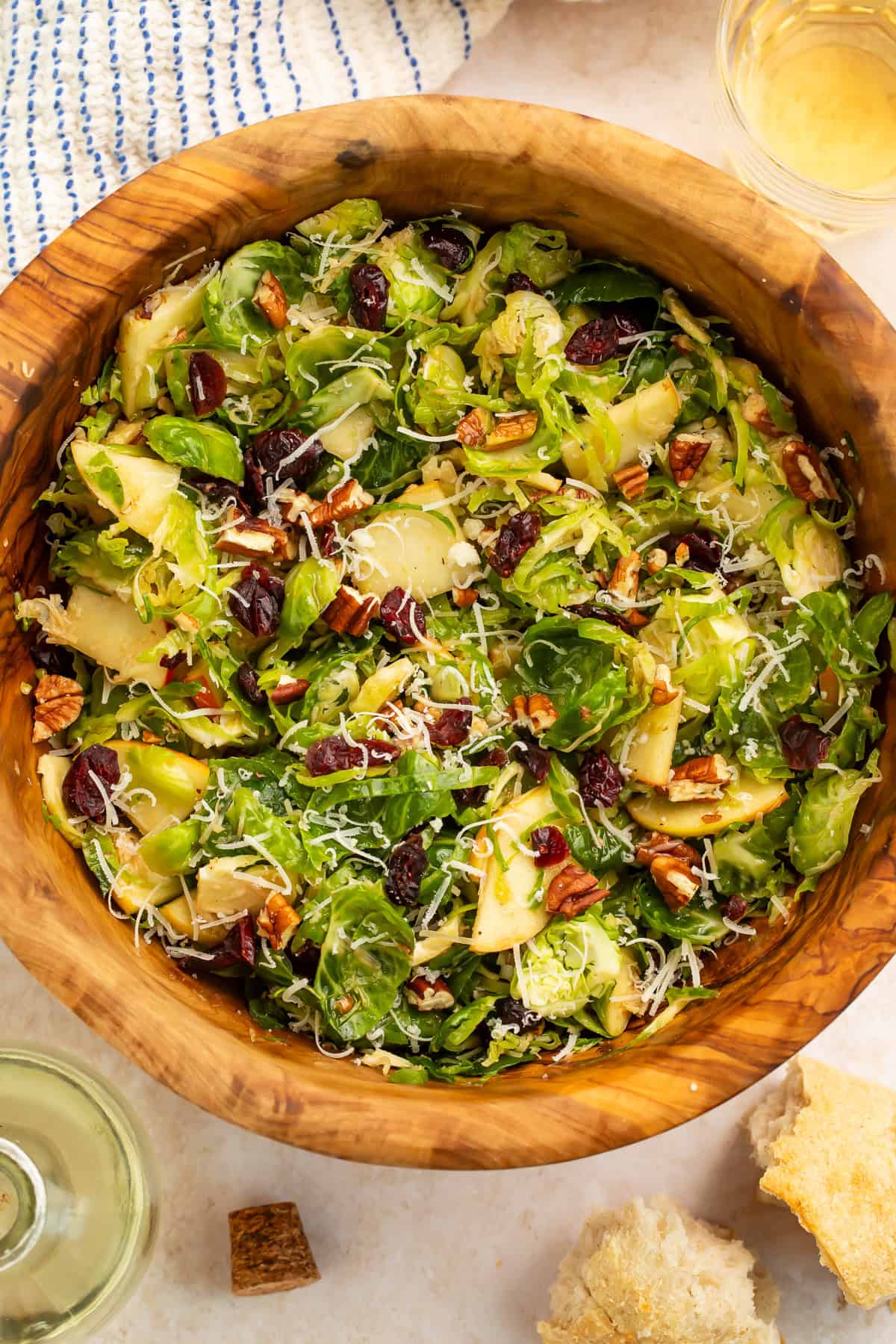 Close up of a shredded sprout salad in a wooden bowl with apples and dried cranberries.