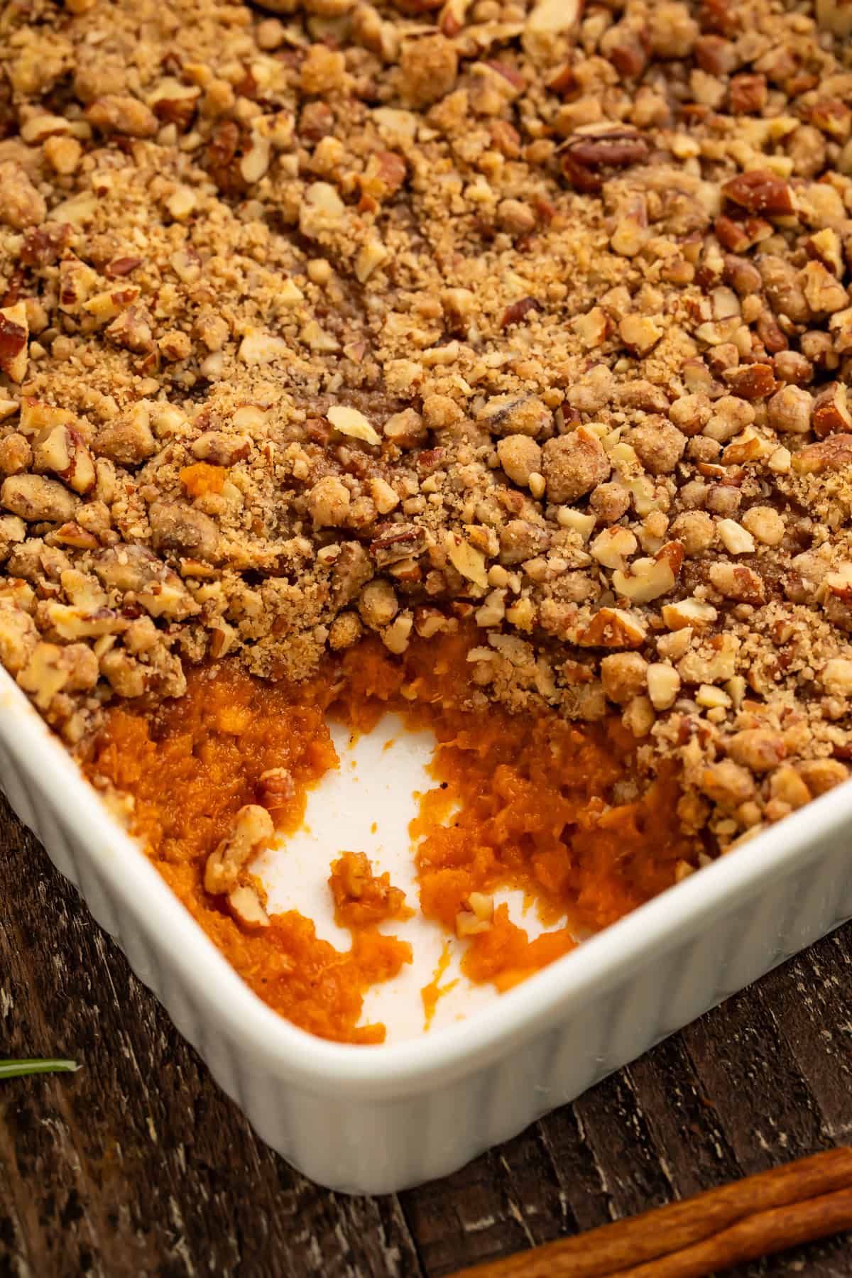 Close up of a sweet potato casserole with a spoonful taken out the corner to show the filling. 