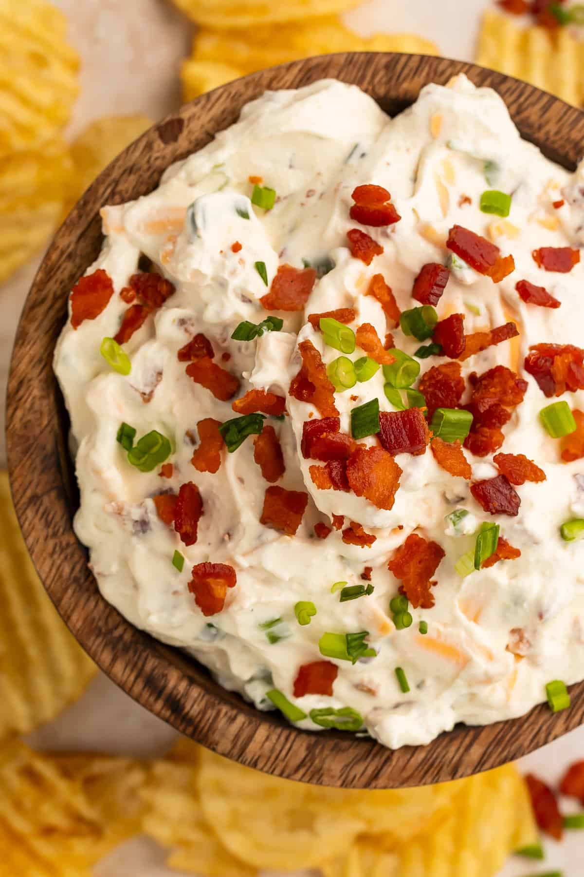 Close up of a creamy loaded baked potato chip topped with bacon bits and green onion.