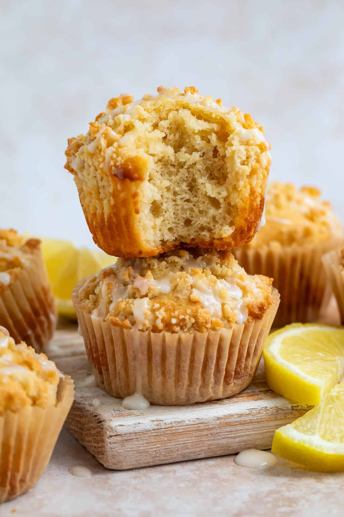 Lemon muffins stacked on top of each other with a bite taken out of the top muffin.