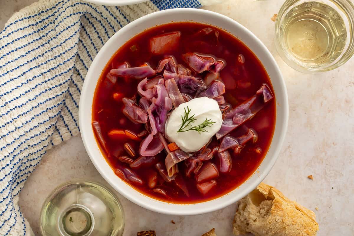 Bowl of cabbage soup pictured next to a blue and white kitchen towel.