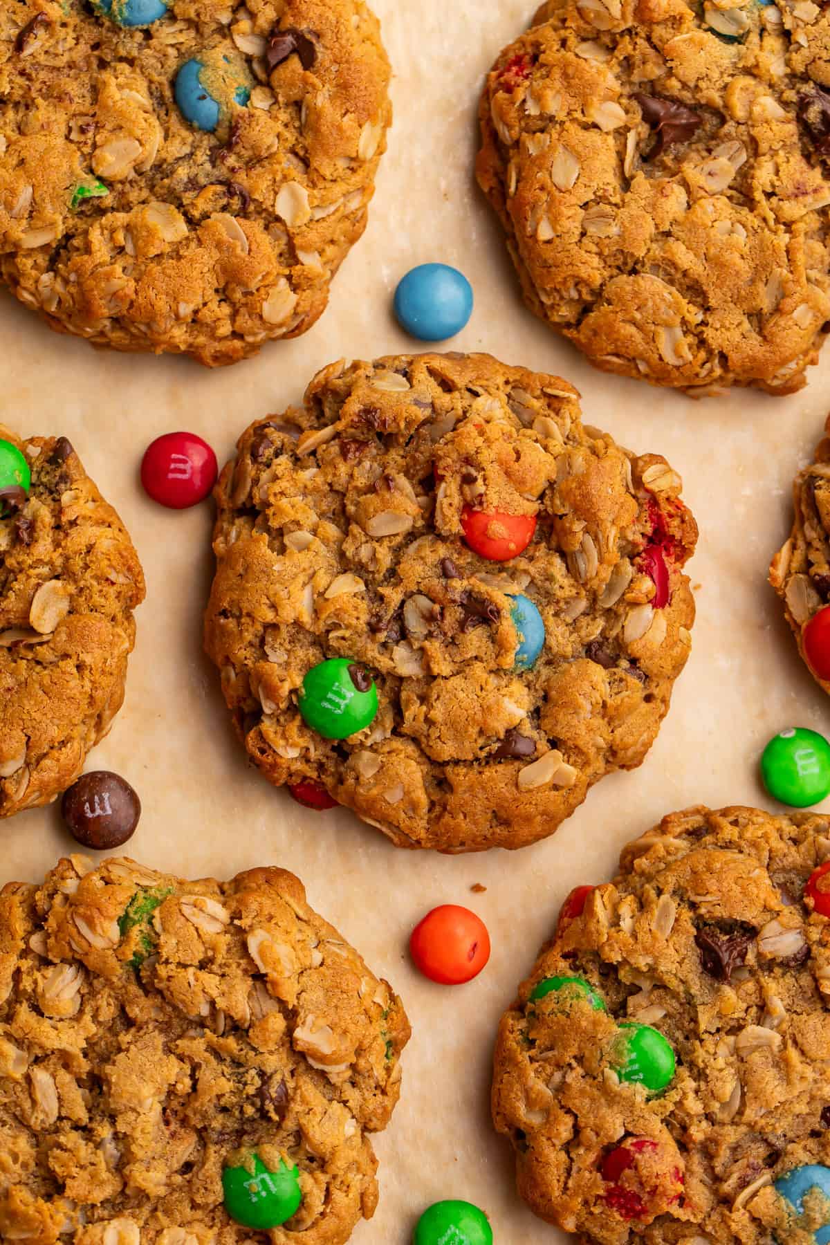 Close up of a batch of monster cookies pictured overhead with M&M candies scattered around them.