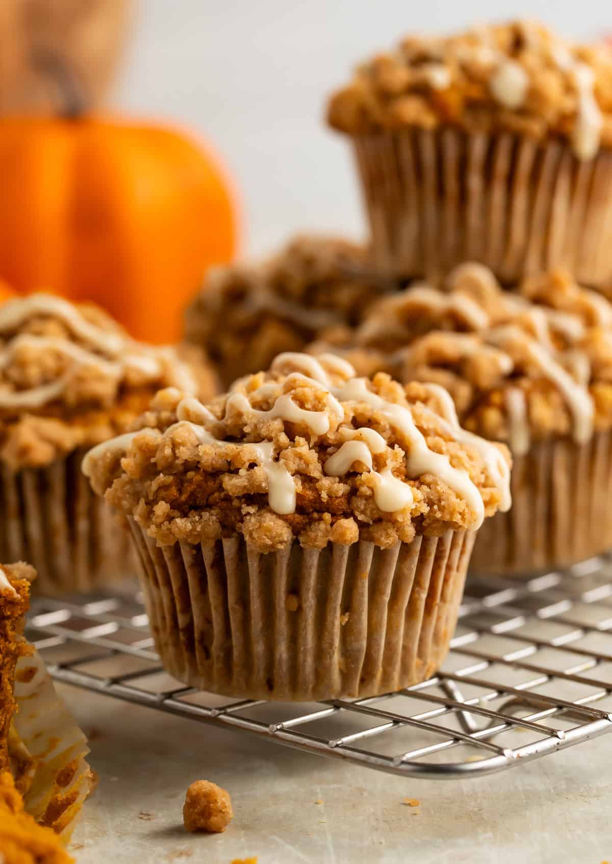 Gluten free pumpkin cupcakes on a cooling rack topped with streusel and a drizzle of glaze.