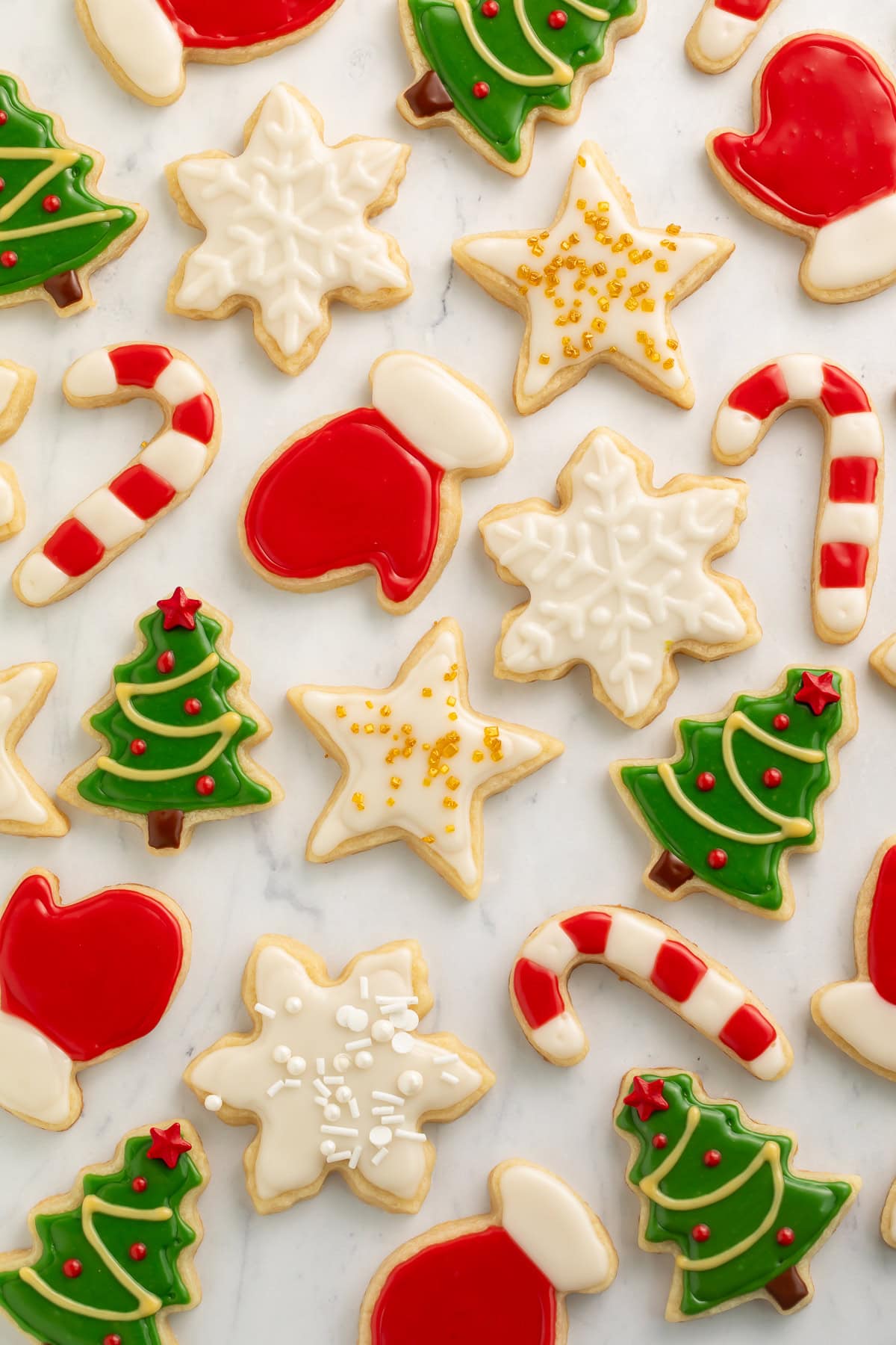 Various vegan decorated Christmas cookies on a white marble background.