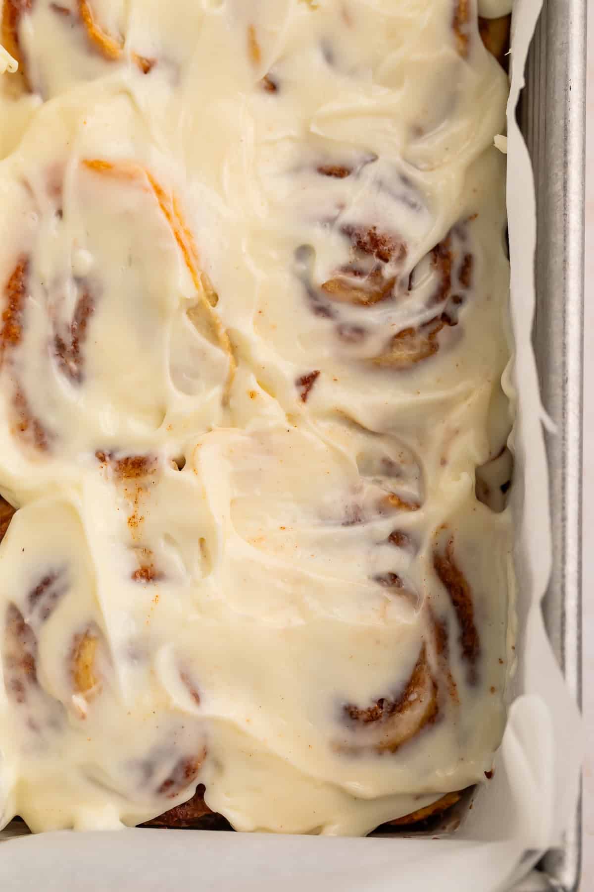 Overhead shot of frosted cinnamon rolls in the pan.