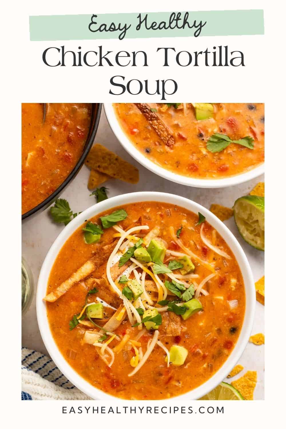 Close up of a bowl of creamy chicken tortilla soup with shredded cheese, chopped avocado and cilantro.
