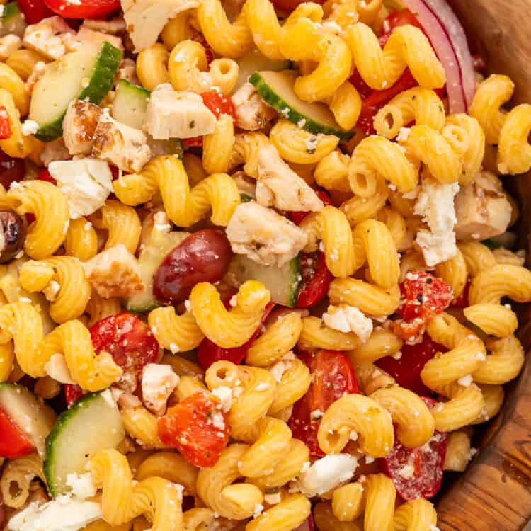 Close up of pasta salad with chicken, onions, olives and feta