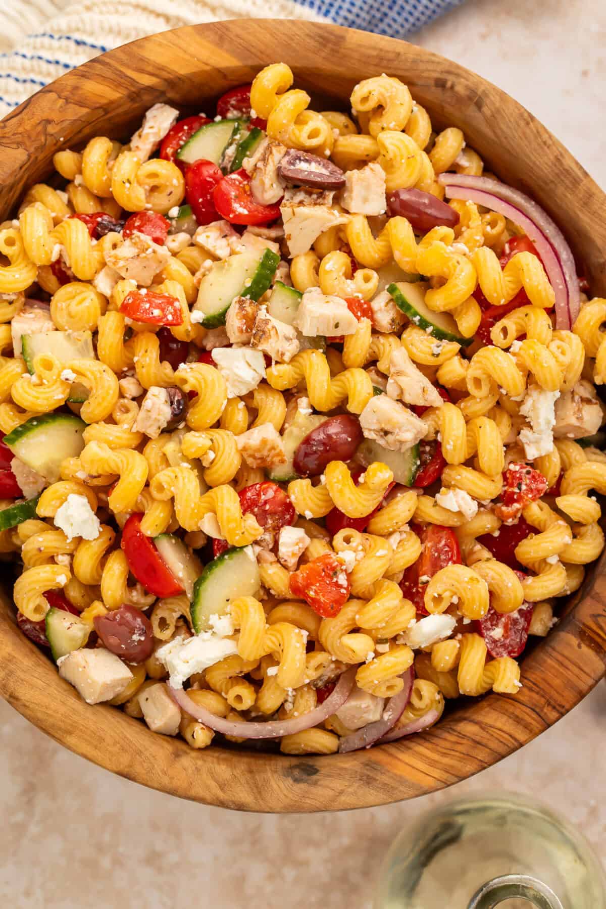 Wooden bowl of Greek-style high protein chicken pasta salad.