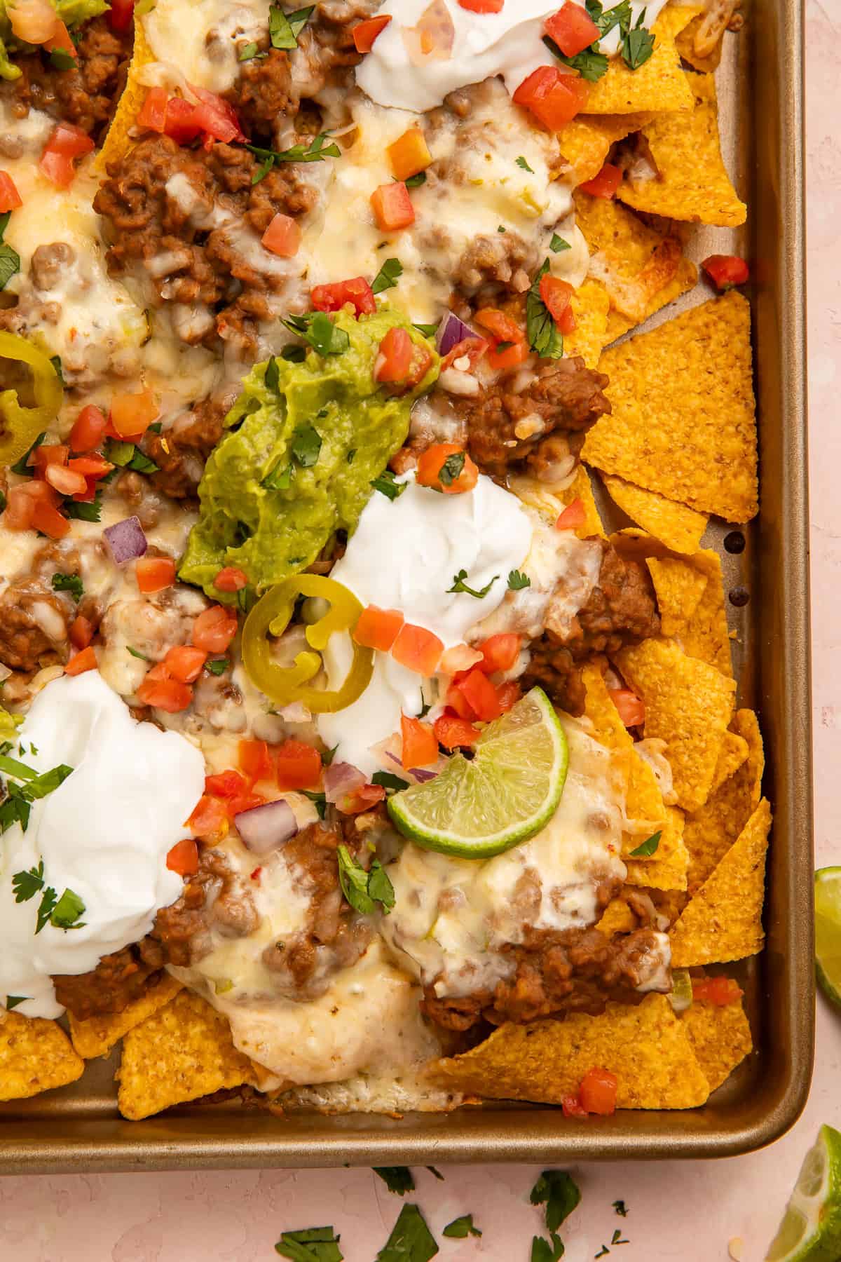 Close up of nachos topped with refried beans, sour cream, cheese, guacamole and salsa.