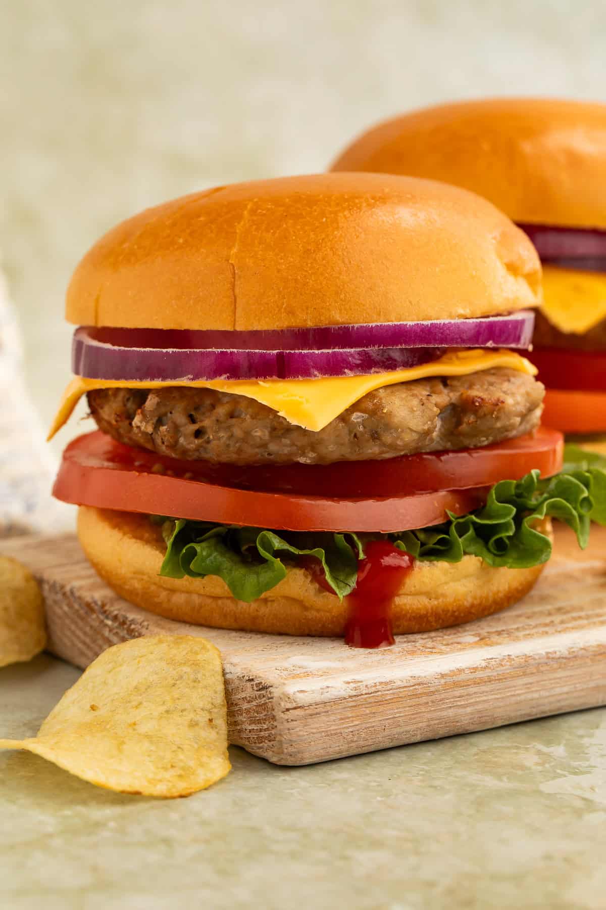 Air fryer turkey burger with cheddar cheese, lettuce, tomato, and red onion served on a brioche bun