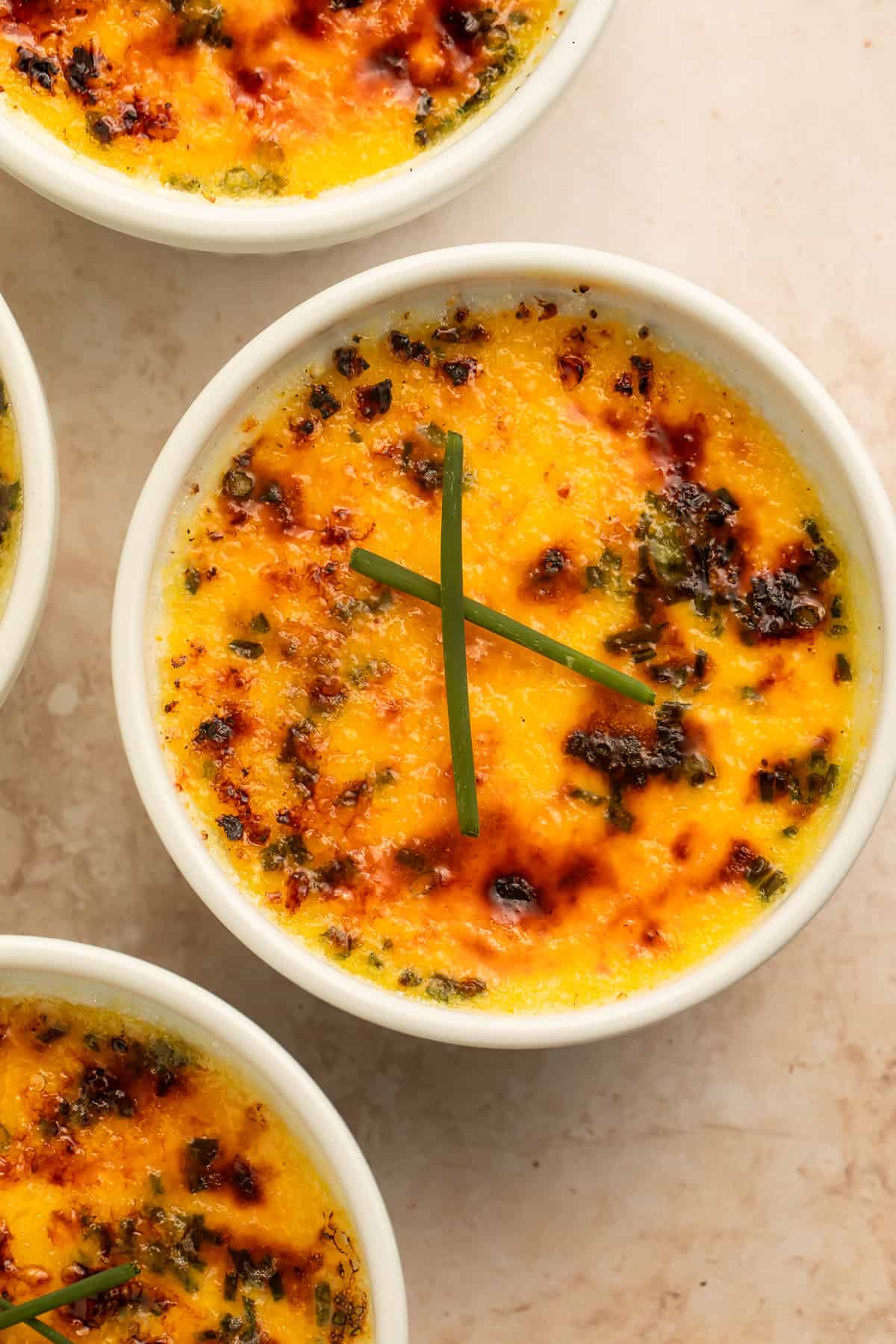 Baked crab brulee ramekins with golden browned tops and chive garnish