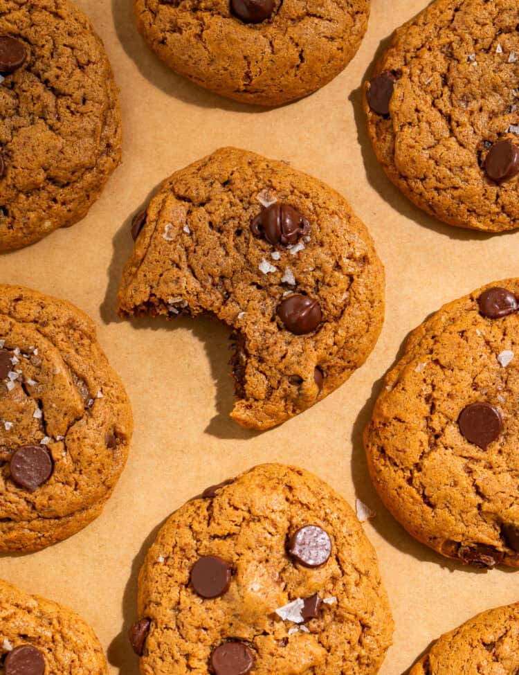 Healthy chocolate chip cookies with dark chocolate chips and flaky sea salt arranged on parchment paper