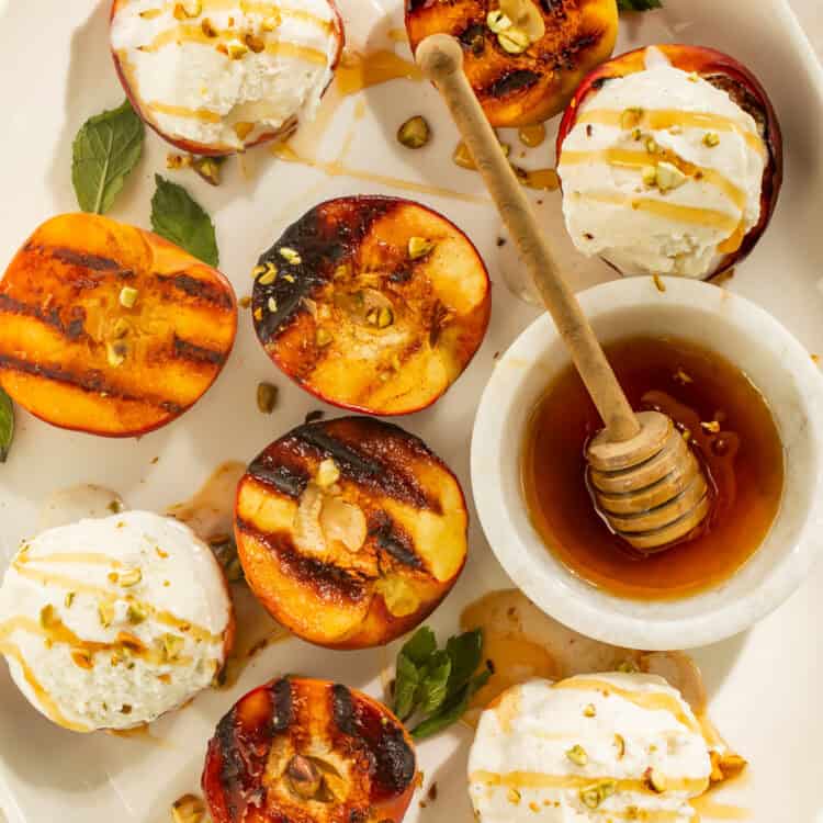 Grilled peaches with vanilla ice cream and honey served on a platter