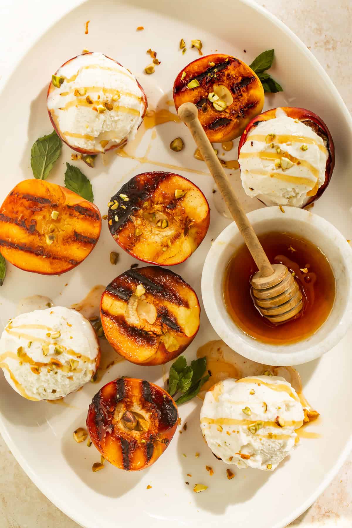 Grilled peaches with vanilla ice cream and honey served on a platter