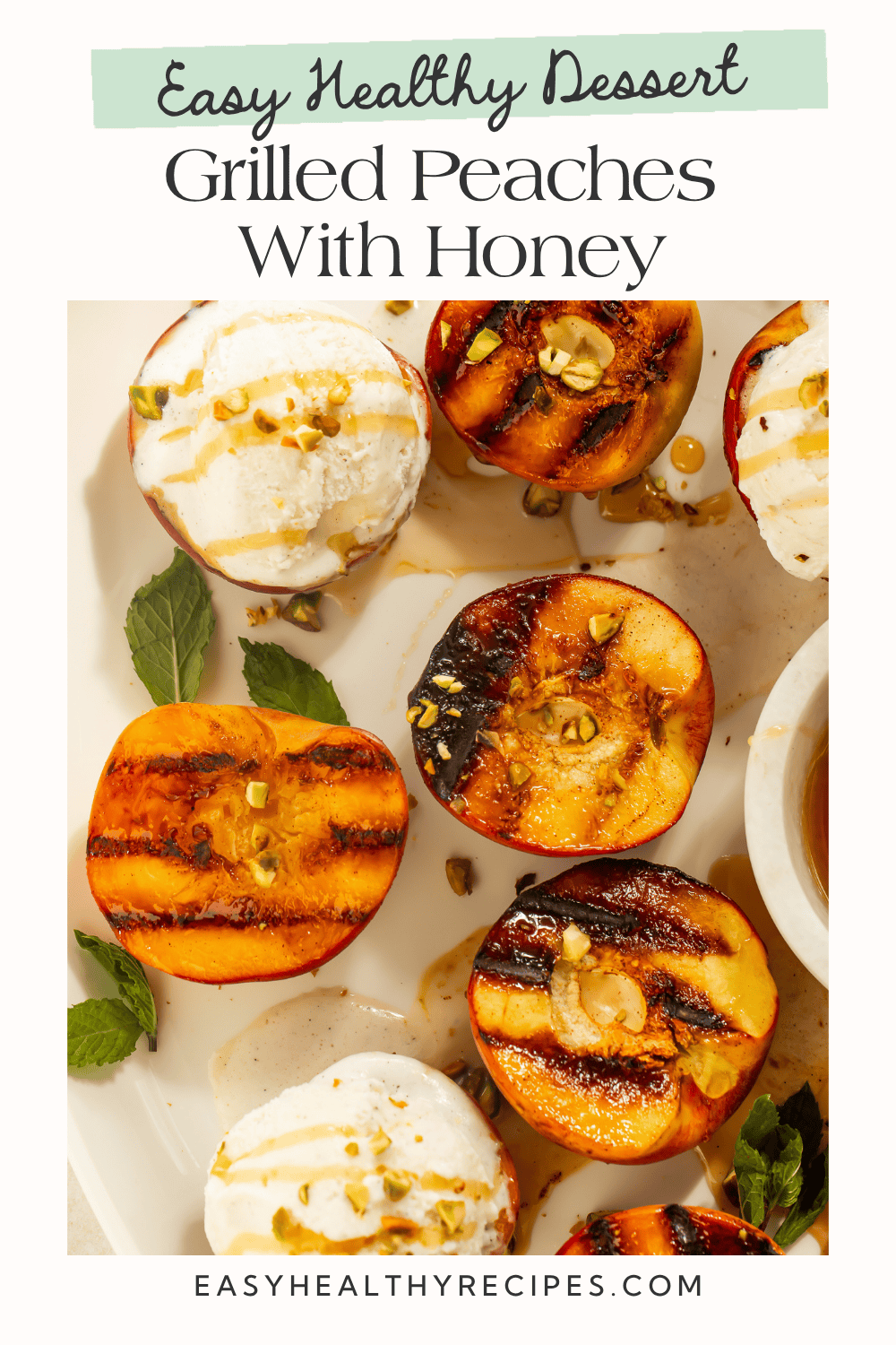 Grilled peach halves and vanilla ice cream scoops on a white platter with a small bowl of honey and honey dipper