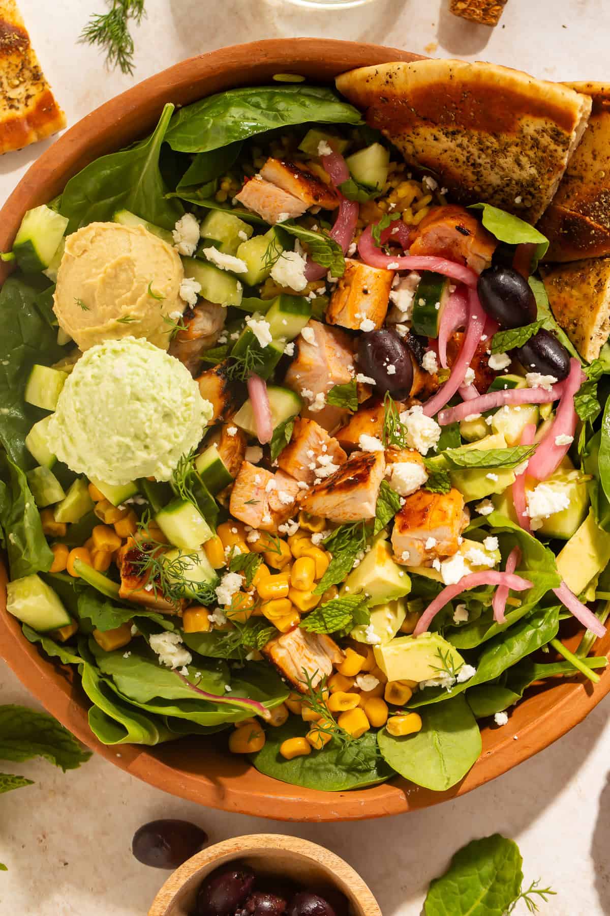Harissa avocado bowl with chicken, Crazy Feta, avocado, cucumber, corn, pickled red onions, feta, and greens
