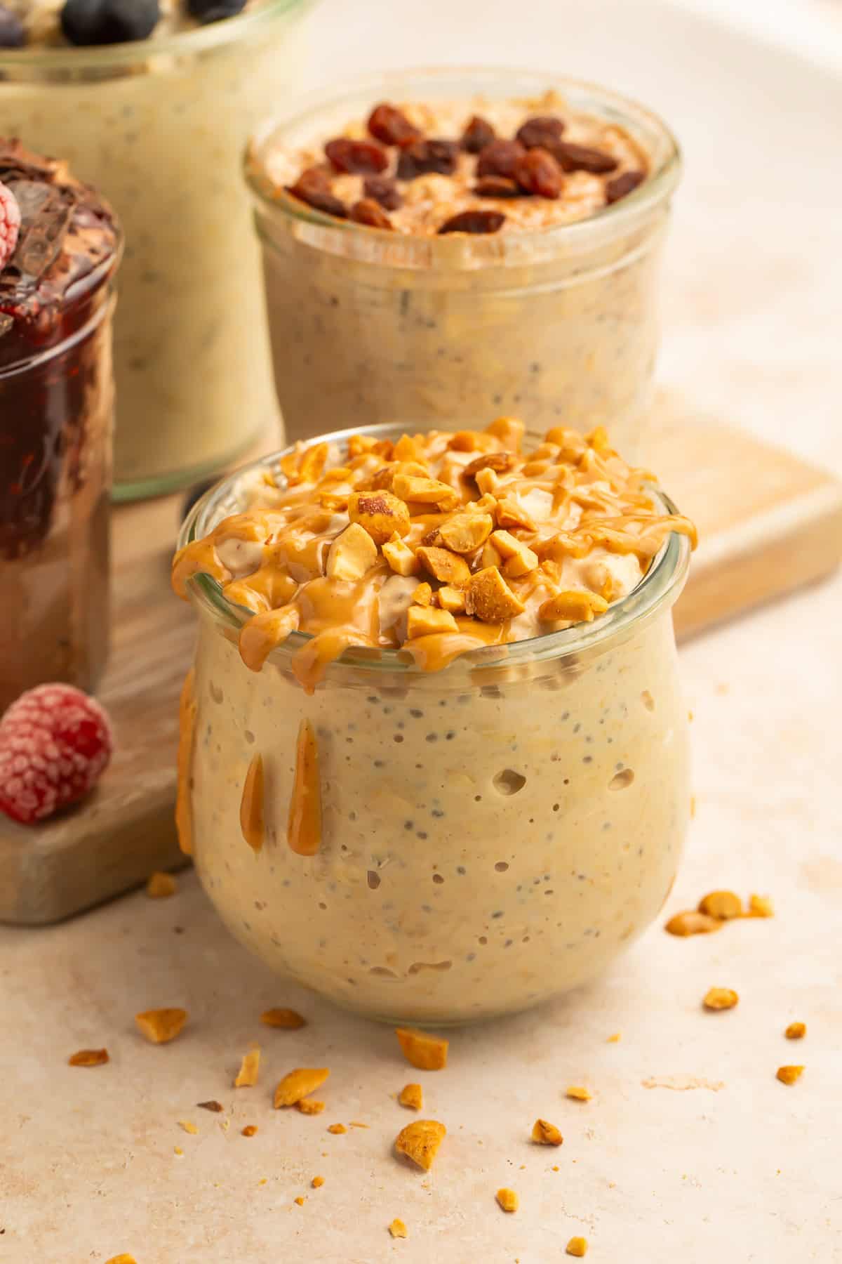 Assorted vegan overnight oats jars with berry, blueberry, raisin, and peanut butter toppings