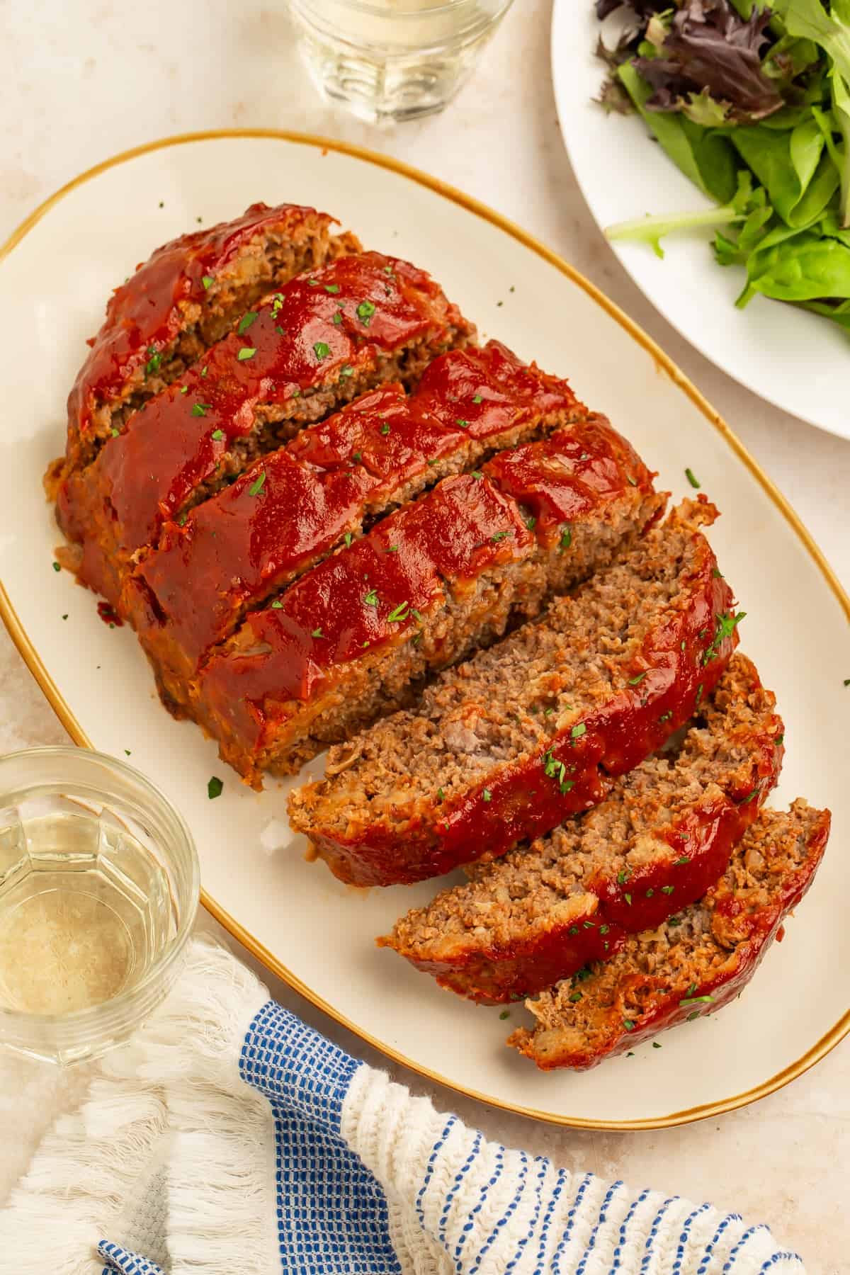 Platter of sliced healthy meatloaf topped with a rich tomato glaze and garnished with fresh parsley.