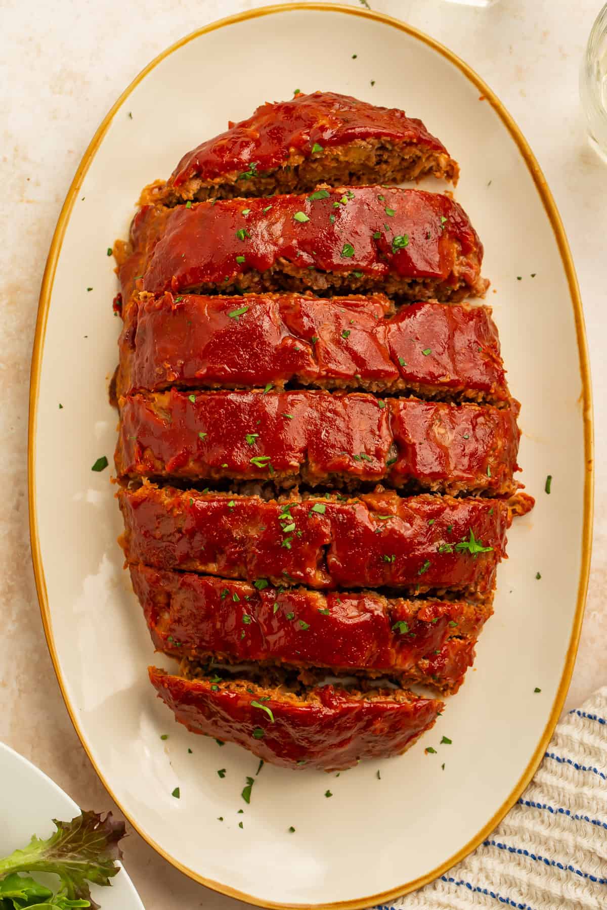 Overhead view of sliced healthy meatloaf covered in a glossy tomato glaze on a serving platter