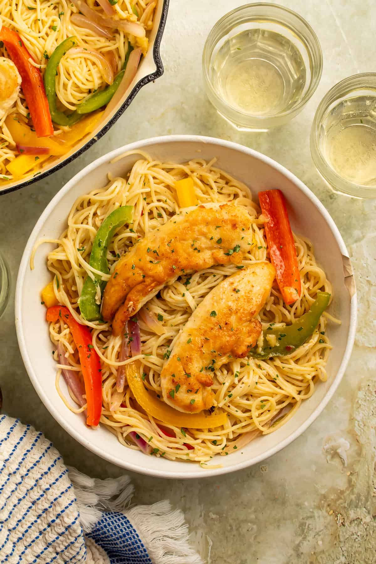 Bowl of Olive Garden chicken scampi with golden chicken tenders, angel hair pasta, colorful peppers, and red onion.