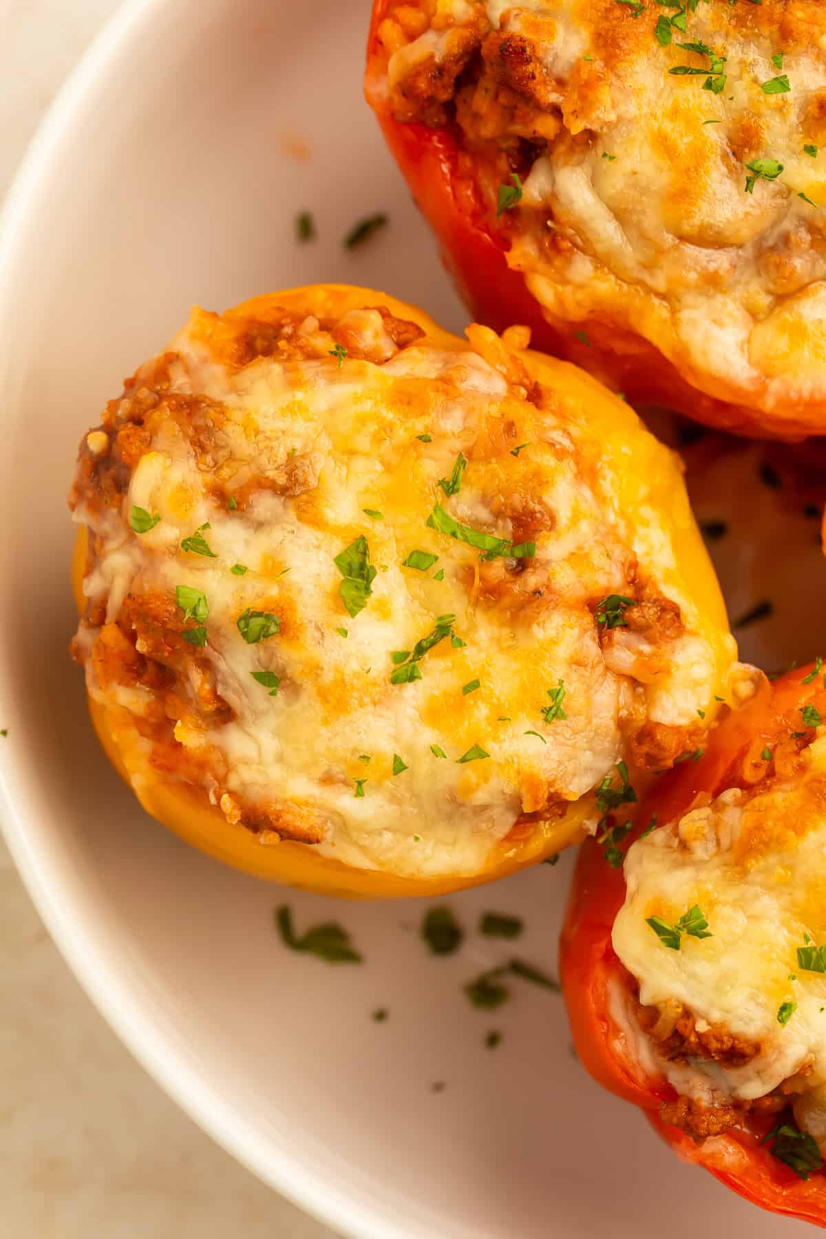 Overhead view of baked stuffed bell peppers filled with a savory turkey and rice mixture, topped with melted golden cheese and fresh parsley in a white baking dish