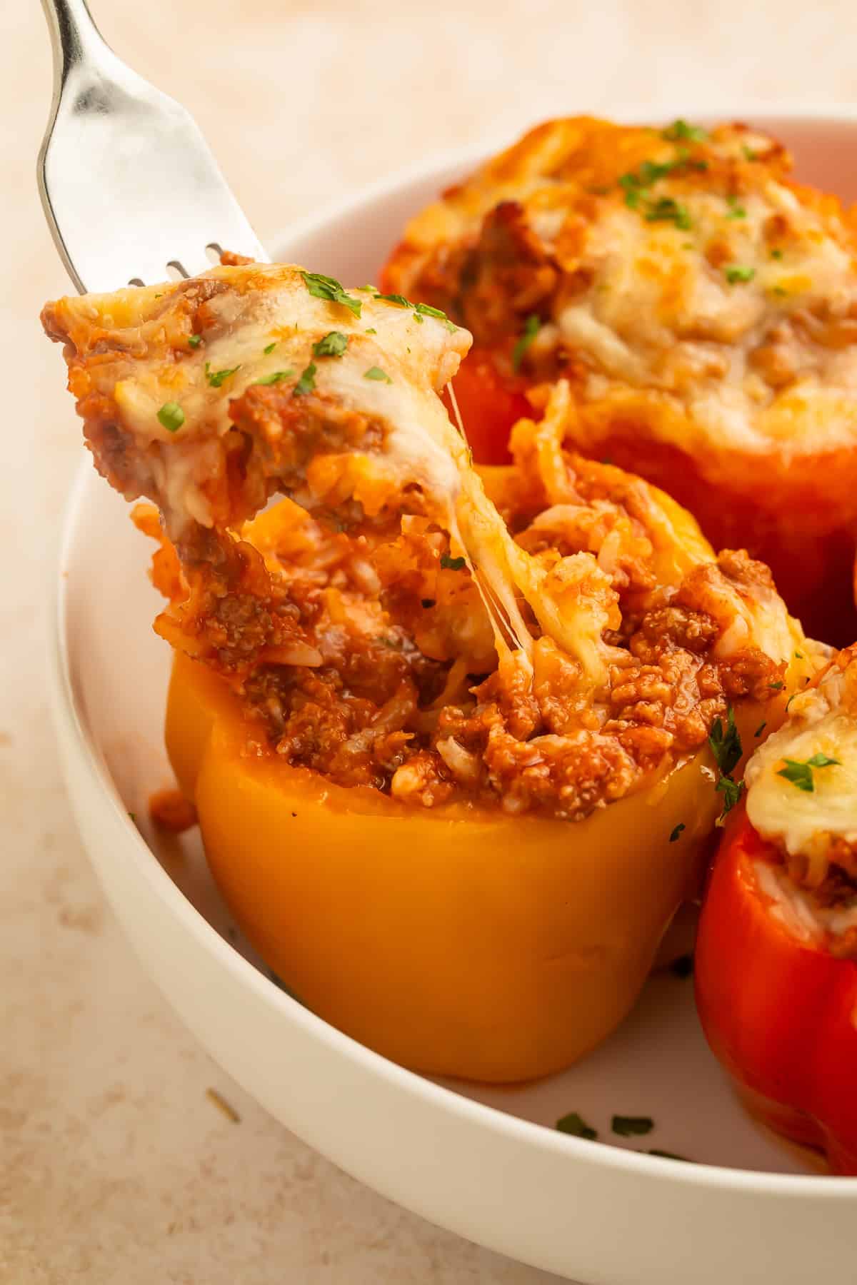A fork lifting a cheesy bite from a baked turkey stuffed pepper, revealing the flavorful turkey and rice filling with melted cheese