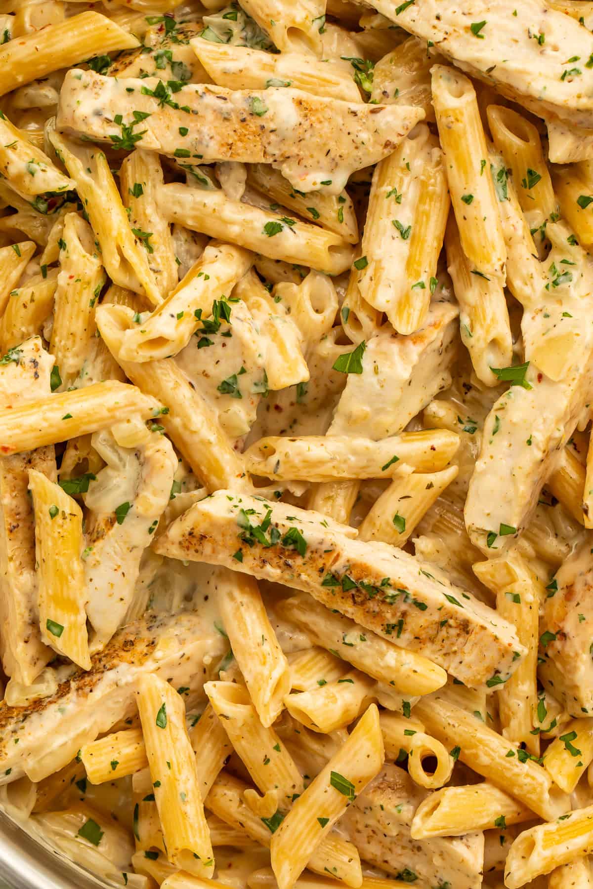 Garlic parmesan chicken pasta with penne, seasoned chicken strips, and fresh parsley.