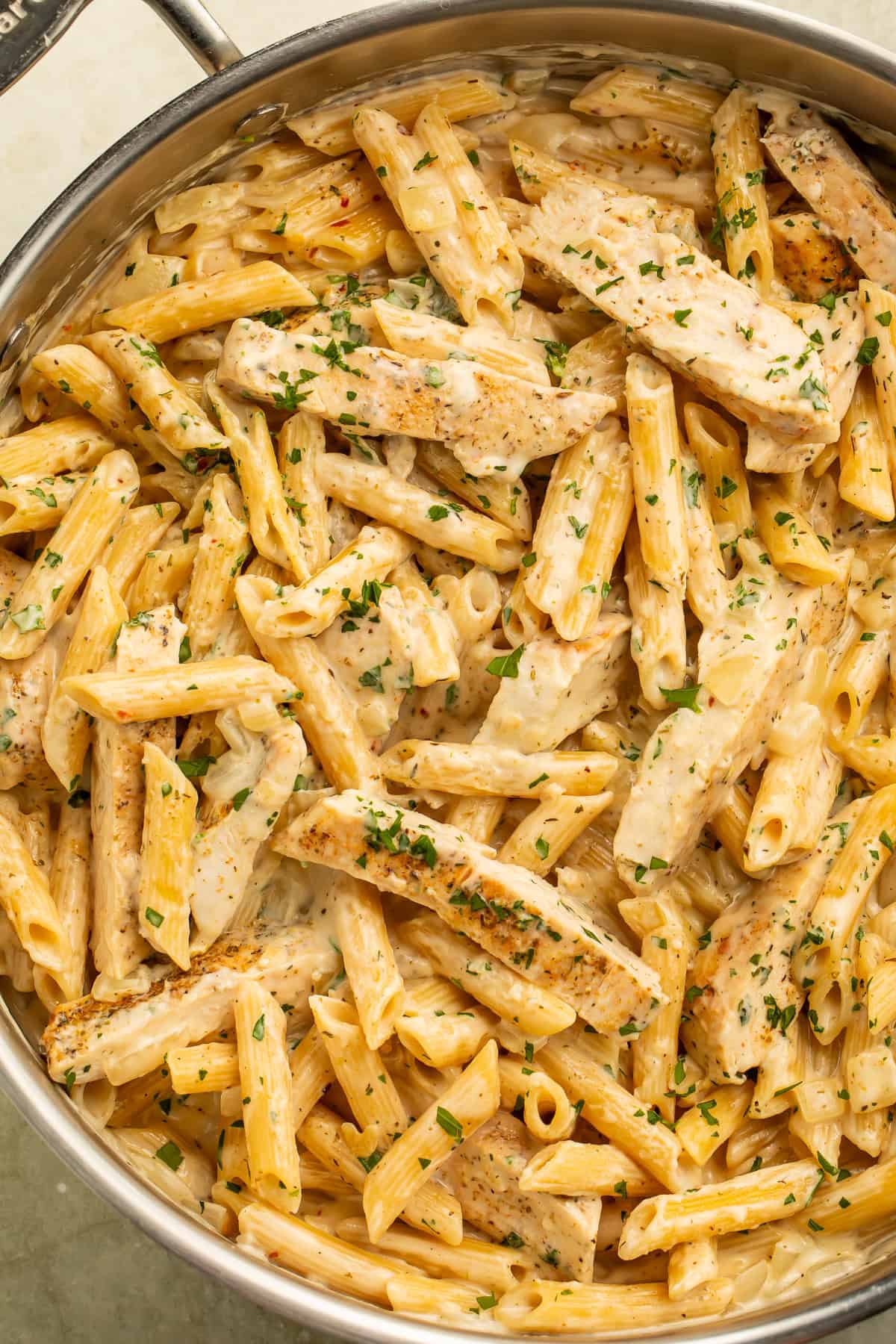 Garlic parmesan chicken pasta with sliced chicken, creamy penne, and parsley.