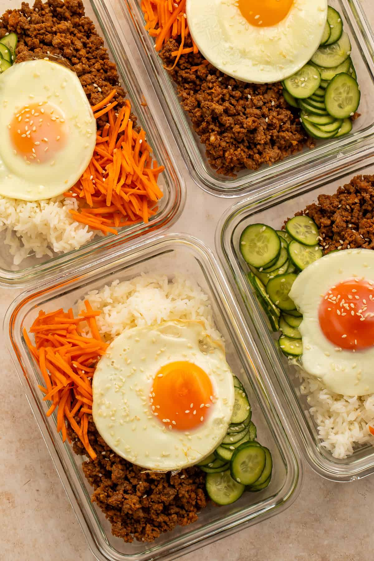 Korean beef meal prep bowls with rice, pickled carrots, sesame cucumbers, and fried eggs