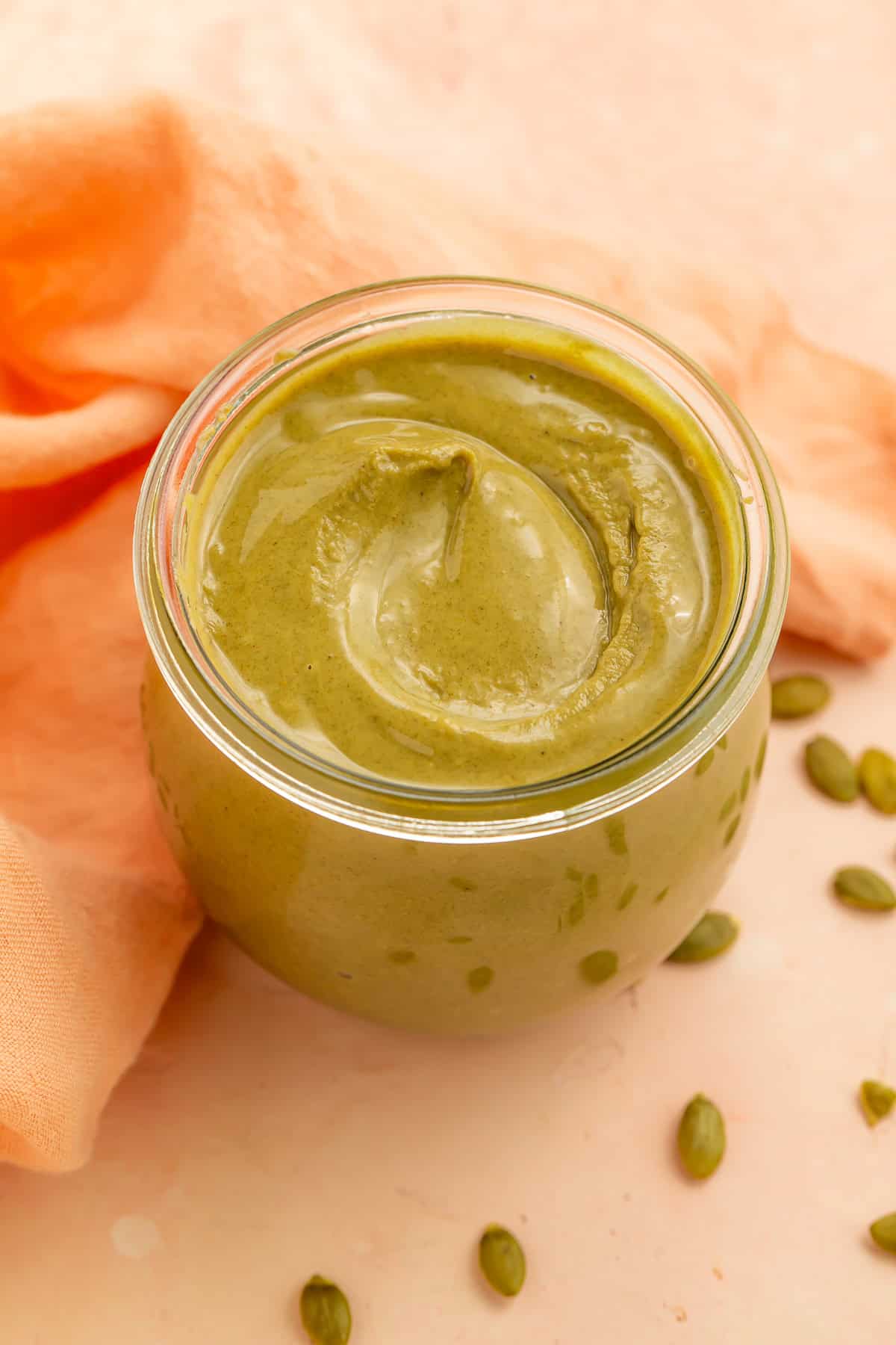 Creamy homemade pumpkin seed butter in a glass jar with scattered pepitas