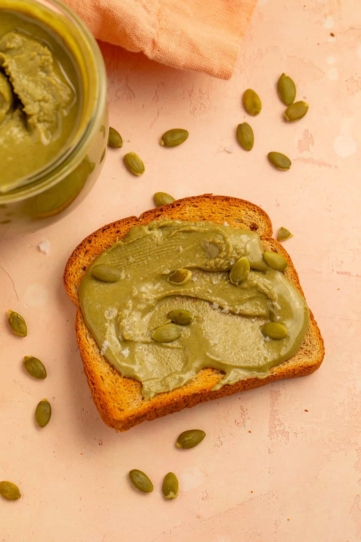 Homemade pumpkin seed butter spread on toast and topped with pepitas