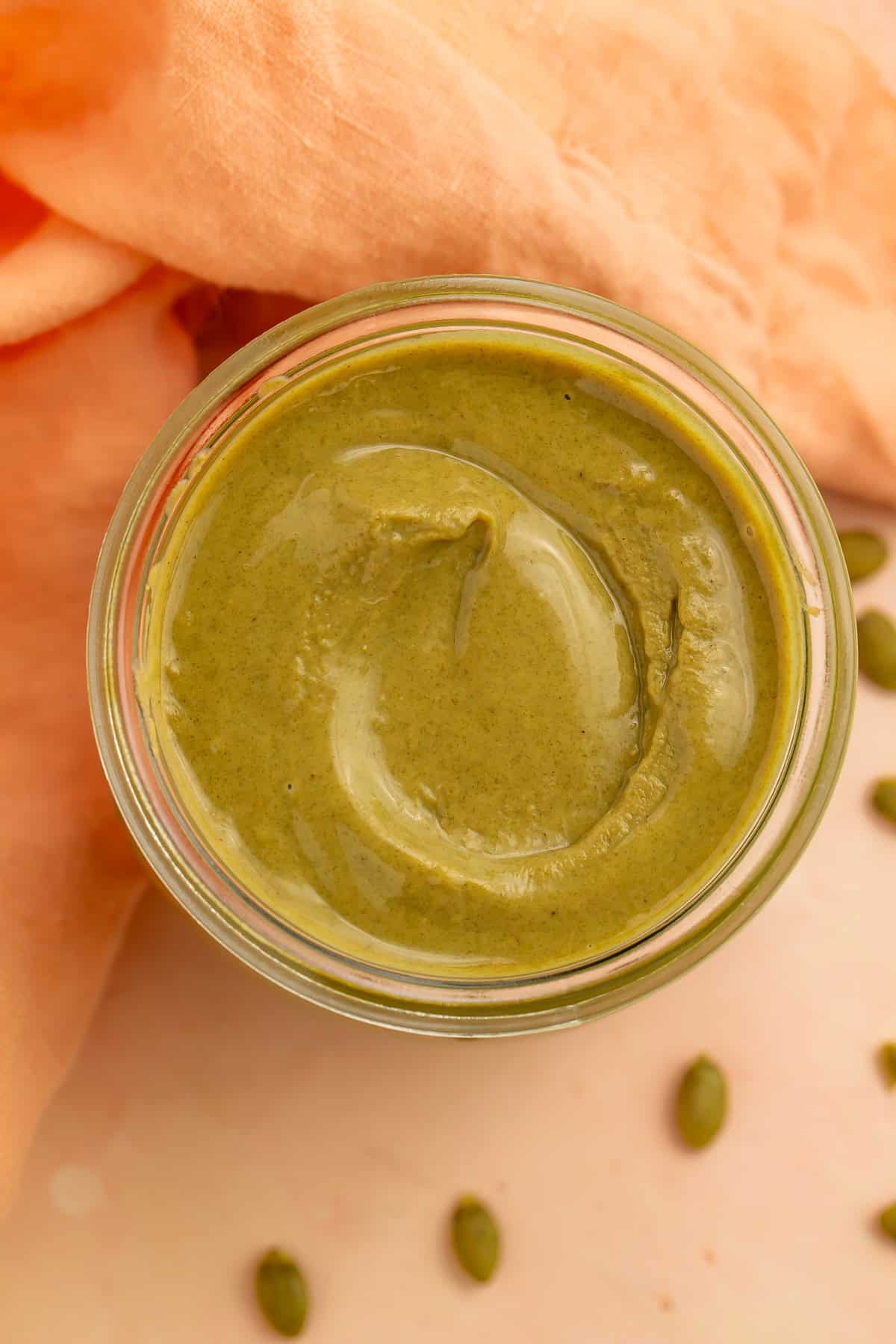 Overhead view of creamy homemade pumpkin seed butter in a glass jar