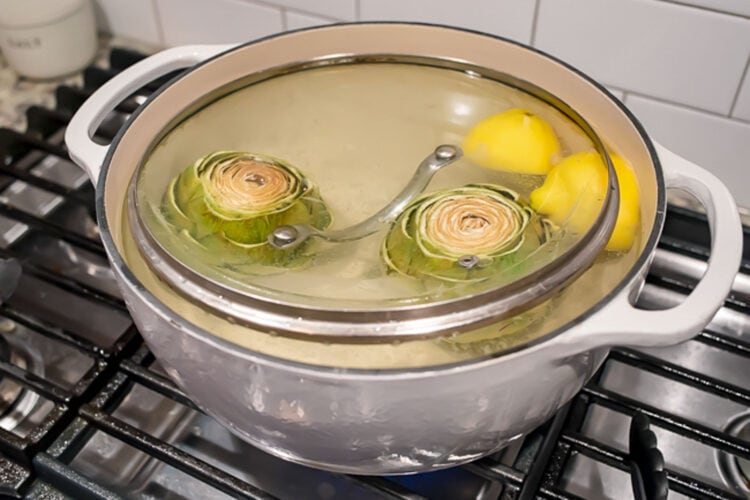 Place artichokes in boiling water and cover with lid to submerge.