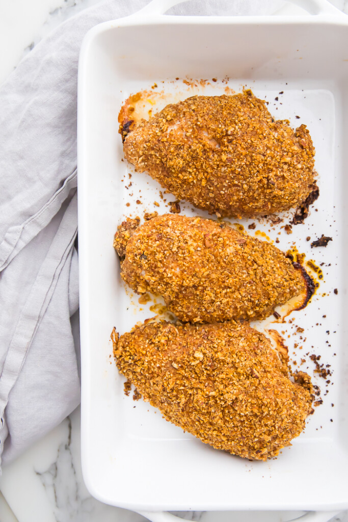 Baked pecan crusted chicken breasts on a white plate