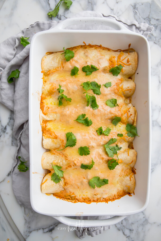 Top shot of creay chicken enchiladas in a white oven dish