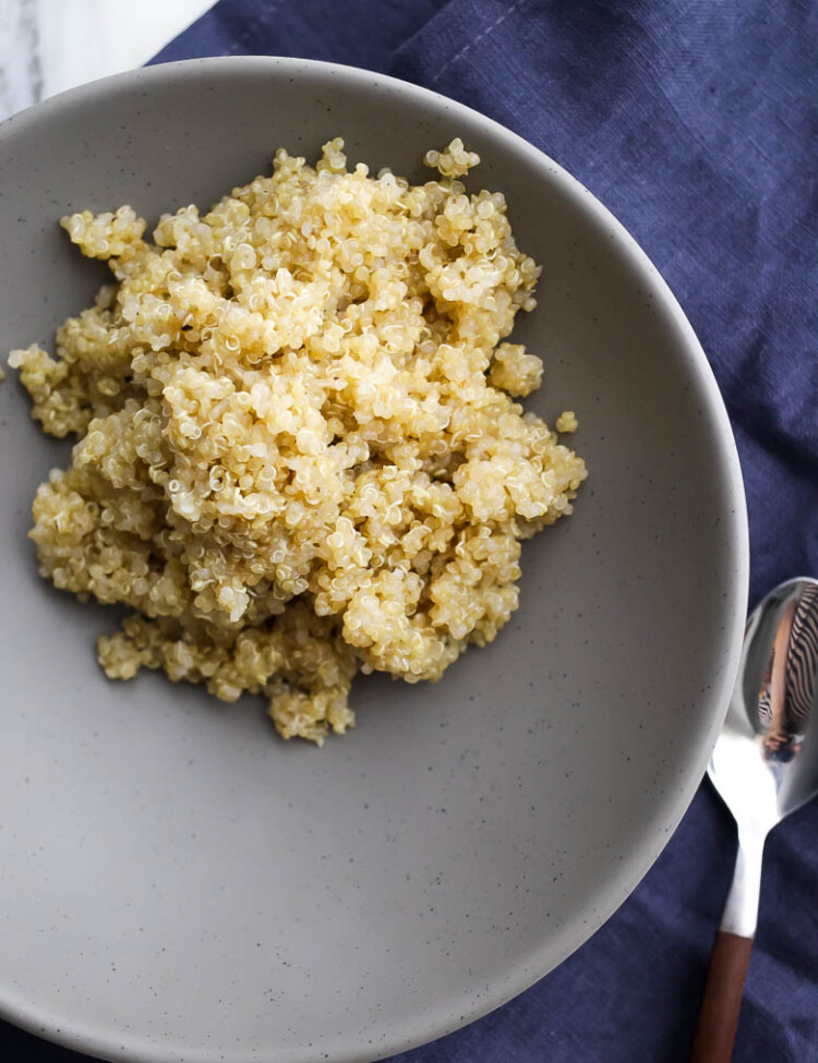 Quinoa on gray plate with navy blue napkin and wooden fork.