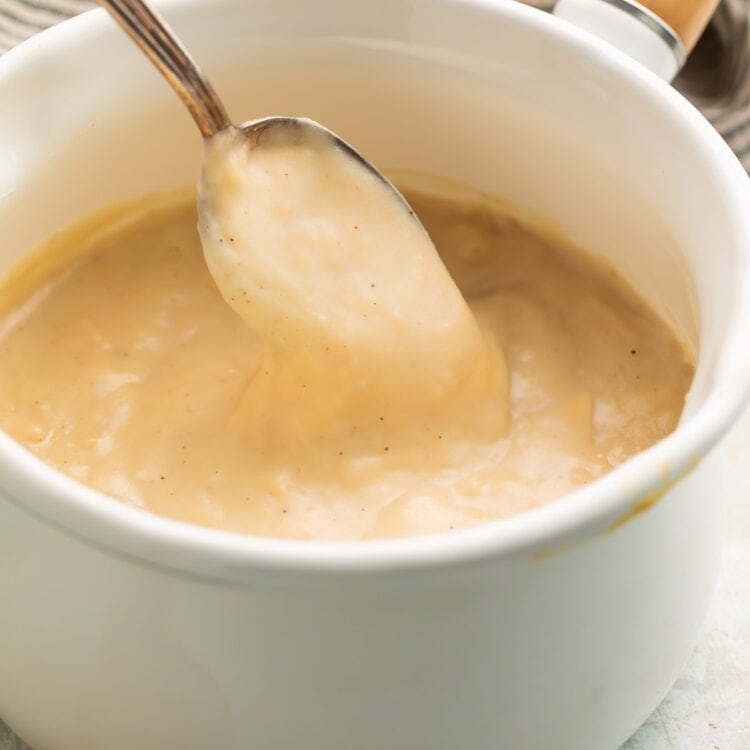 A spoonful of gluten-free cream of chicken soup being lifted out of a pot of condensed soup.