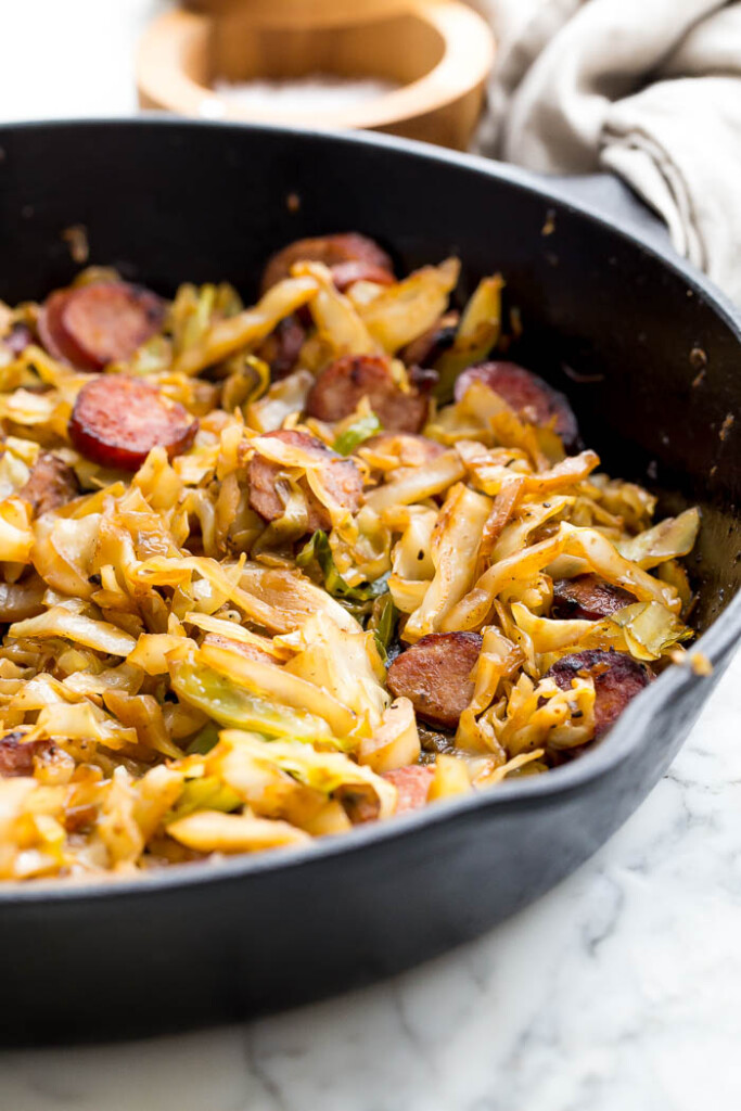 close up photo of kielbasa and cabbage in cast iron skillet.