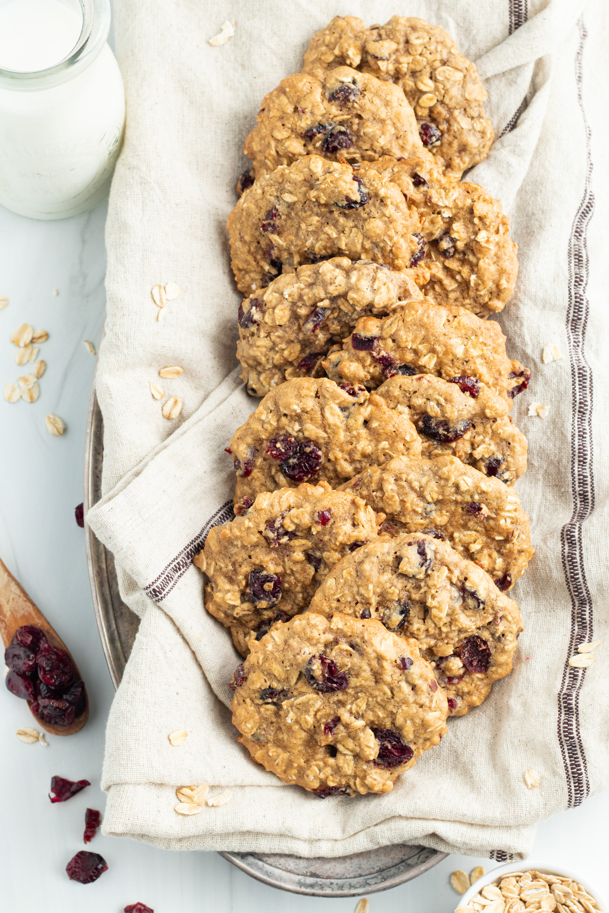 Overhead view of oatmeal cranberry cookies in a napkin-lined basket on a table.