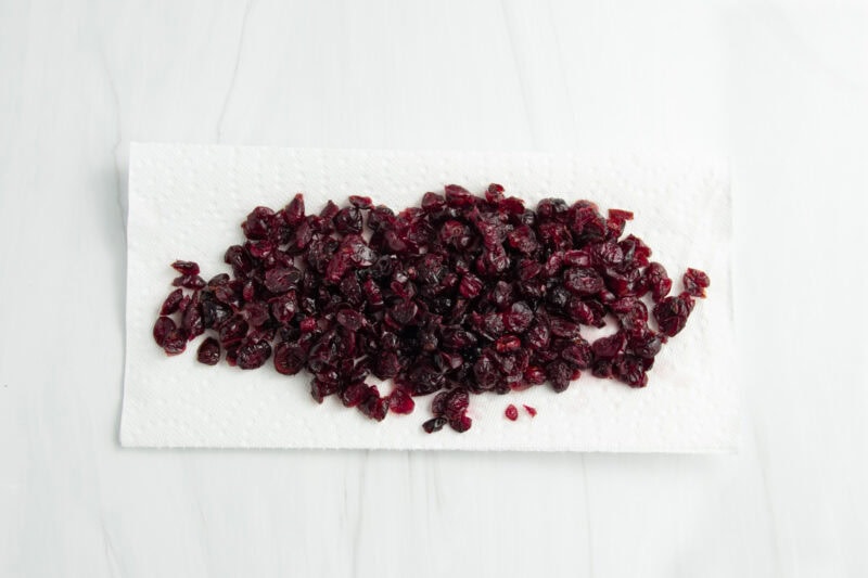 Overhead view of rehydrated cranberries resting on paper towels to drain excess water.