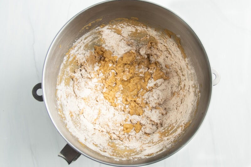 Overhead view of a silver stand mixer bowl with gluten free flour added to creamed butter and sugar.