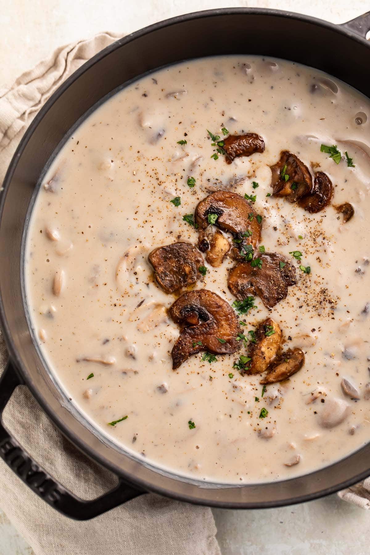 A large pot of creamy gluten free cream of mushroom soup with sautéed mushrooms garnishing the top.