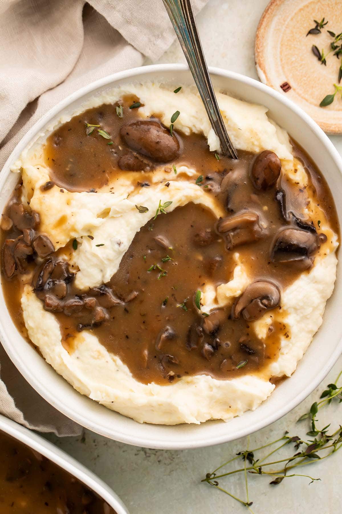 A large bowl of mashed potatoes topped with rich brown vegan mushroom gravy.