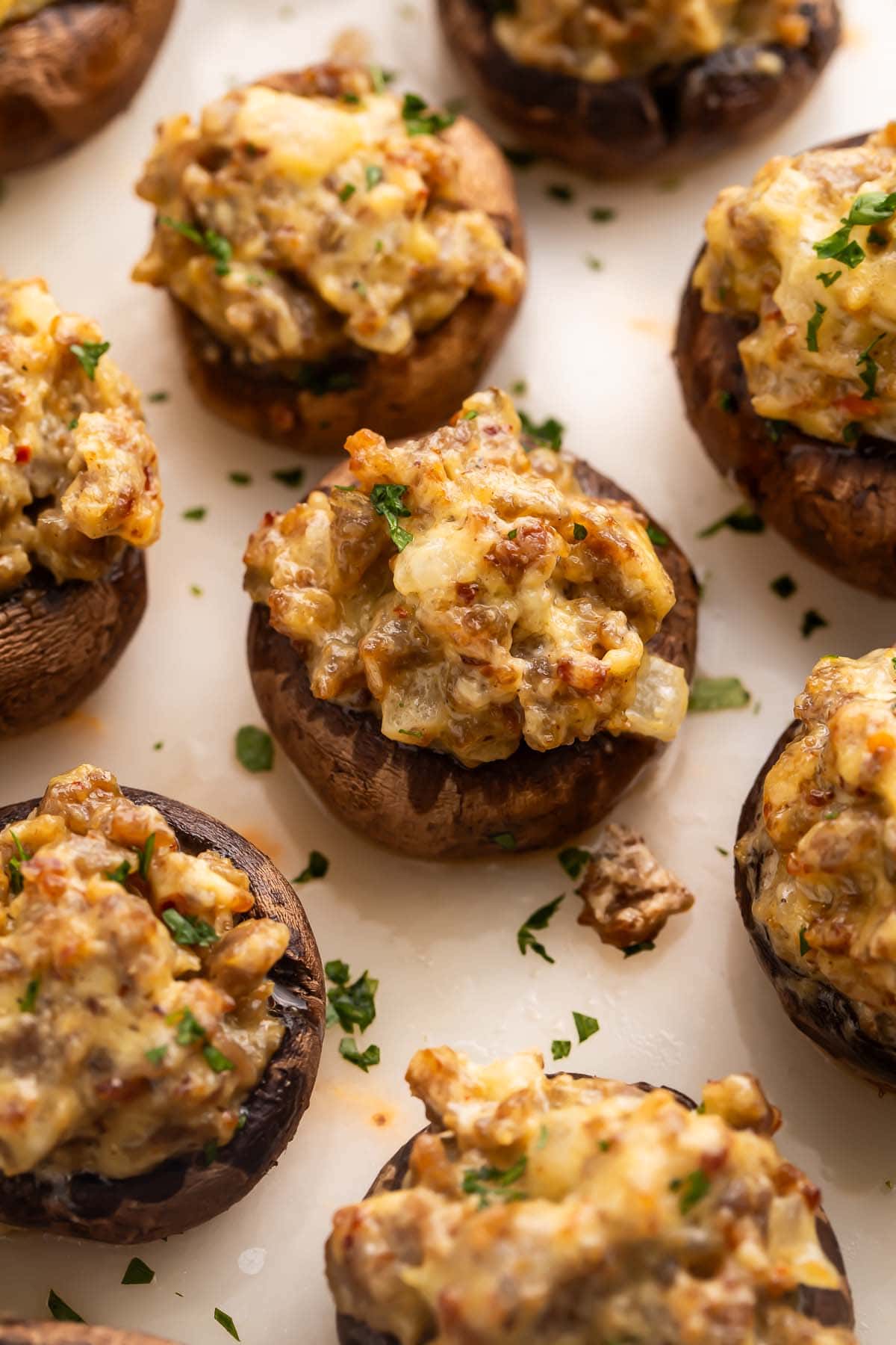 Close-up on a sausage stuffed mushroom on a platter with other stuffed mushrooms.