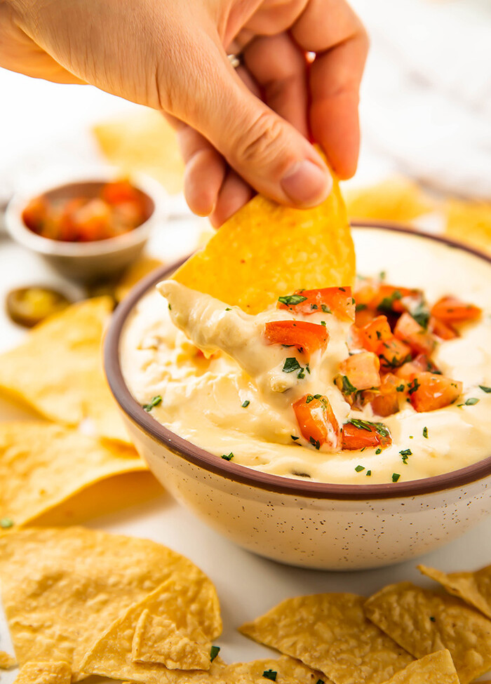 A chip being dipped into Crockpot queso dip