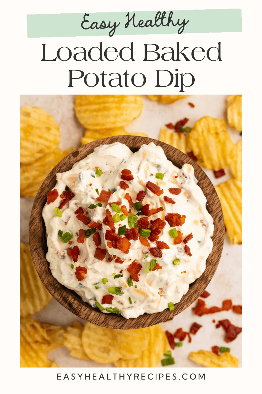 Close up of a wooden bowl of loaded baked potato dip with scattered potato chips around it. There is a Pinterest-optimised tex overlay.