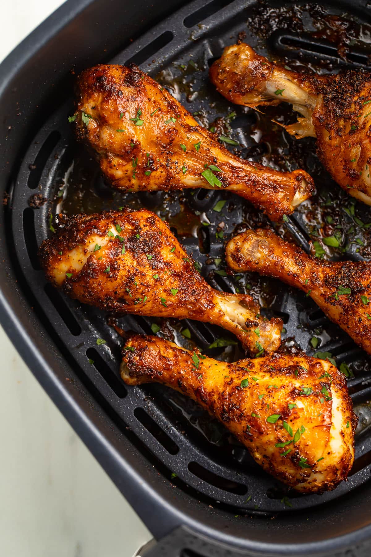 Air fryer chicken legs in a black air fryer basket.