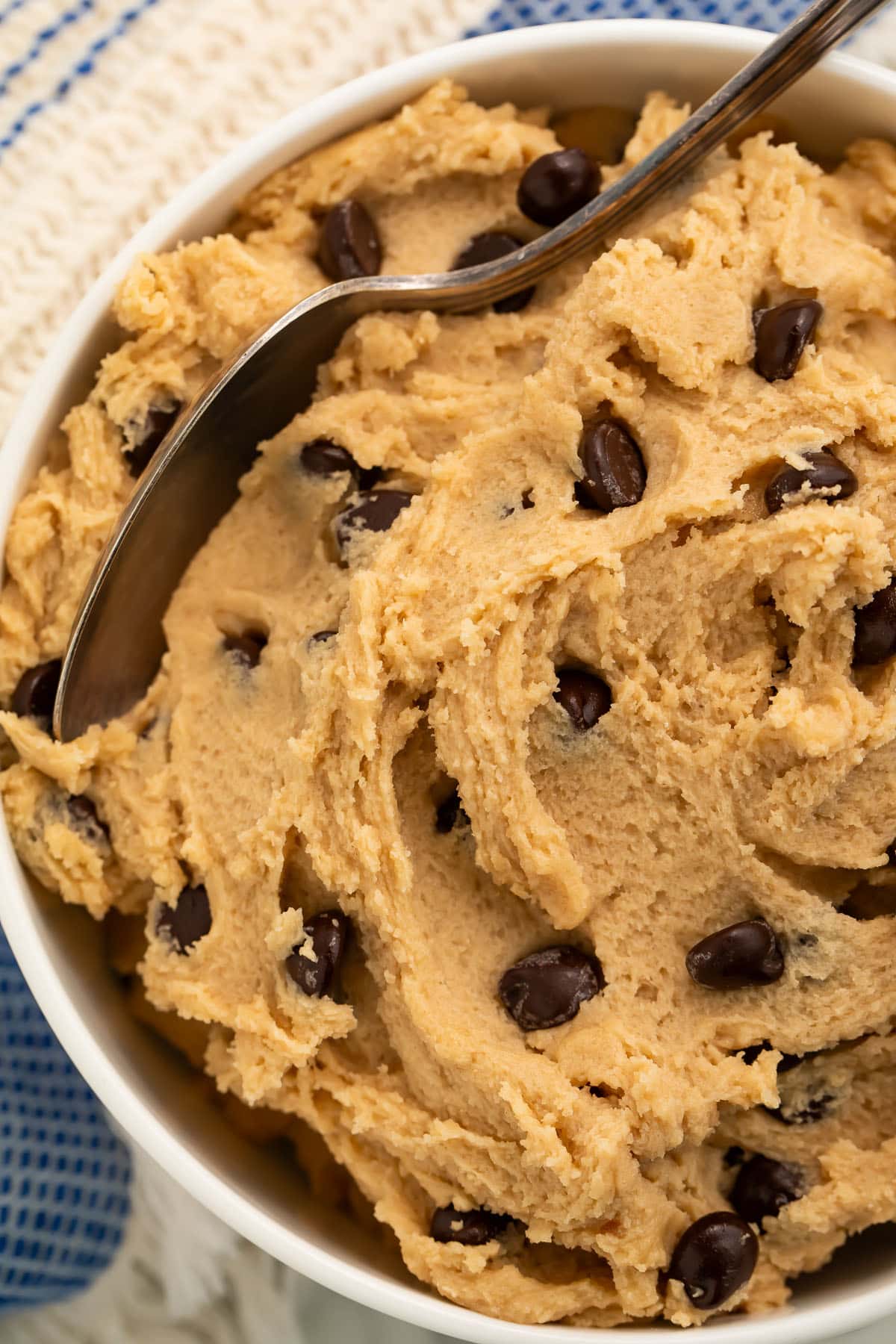 Close-up of a bowl of edible vegan cookie dough with a spoon resting in the dough.